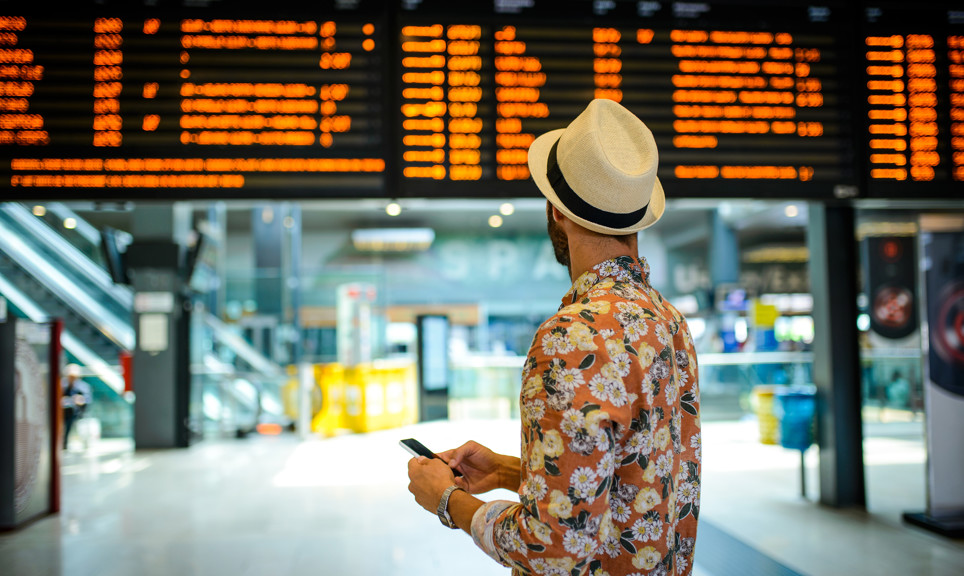Tourist man with the hat looking at the timetable board