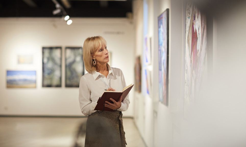 Waist up portrait of elegant mature woman looking at paintings in art gallery hall and enjoying museum exhibition, copy space