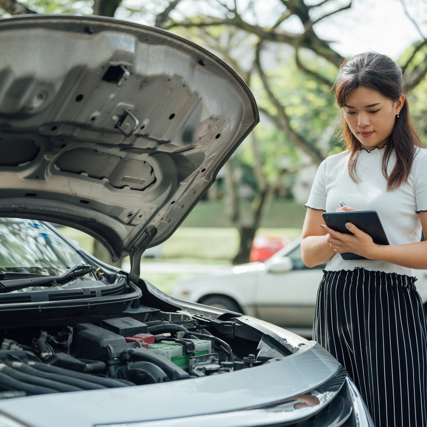 Automobile insurance adjuster using digital tablet to inspecting damage to vehicle.